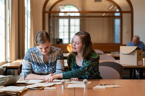 Twee vrouwelijke studenten bekijken een stapel papieren